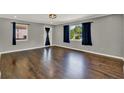 Well-lit living room featuring dark hardwood floors, freshly painted walls, and two large windows at 2209 Hutchinson Ave, Leesburg, FL 34748