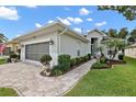 Charming single-story home with a well-maintained lawn and brick driveway under a blue sky at 3584 Tropical Seas Loop, Tavares, FL 32778