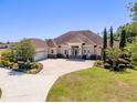 Beautiful single-story home showcasing a circular driveway, lush landscaping, and a three-car garage at 41522 Saddle Ridge Ln, Weirsdale, FL 32195