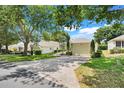 Lovely single-story home featuring a manicured lawn, mature trees, and a spacious two-car garage at 4167 Capland Ave, Clermont, FL 34711