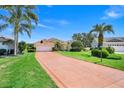 Charming one-story home featuring a long driveway, well-manicured lawn, and tropical palm trees at 4720 Summerbridge Cir, Leesburg, FL 34748