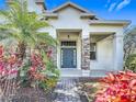 Inviting front entrance with stone accents, a beautifully colored door, and lush tropical landscaping at 4908 Cape Hatteras Dr, Clermont, FL 34714