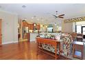 Open-concept living area with hardwood floors, ceiling fan and view into the kitchen at 6104 Hunters Ridge Ave, Leesburg, FL 34748