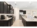 Modern kitchen with dark cabinets, stainless steel appliances, and white countertops at 8024 Oak Shadow Ct, Davenport, FL 33837