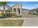 Charming home with two-car garage, stone accents, manicured landscaping, and a brick-paved driveway at 8272 Procida Isle Ln, Windermere, FL 34786