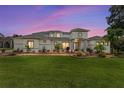 Beautiful home features a manicured lawn, well-maintained landscaping, and a modern architectural style at twilight at 1111 Myrtle Breezes Ct, Fruitland Park, FL 34731