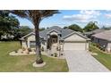 Charming single-story home boasts a paved driveway, two-car garage, and manicured landscaping under a clear sky at 1329 Gaston Loop, The Villages, FL 32162