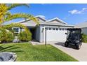 A well-maintained single-story home featuring a two-car garage and an adjacent golf cart at 1633 Manserra St, The Villages, FL 32163