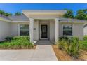 Covered front porch features decorative door, manicured bushes, and matching windows at 16380 Se 84Th Ct, Summerfield, FL 34491