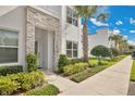 A modern townhome with stacked stone accents, lush landscaping, and a well-manicured lawn at 17519 Hidden Forest Dr, Clermont, FL 34714