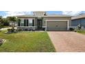 Charming single-story home featuring a brick driveway, manicured lawn, and a mix of stone and siding accents at 456 Winter Solstice Ln, Mount Dora, FL 32757