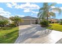 Wide driveway leading to a two-car garage, framed by a well-manicured lawn and landscaping at 857 Enisgrove Way, The Villages, FL 32163