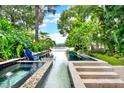 Tranquil pool with a lake view surrounded by lush greenery and blue Adirondack chairs at 9642 Bear Lake Rd, Apopka, FL 32703