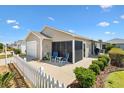 Charming backyard with white picket fence, screened lanai, landscaped yard, and patio with outdoor seating at 1486 Olympia St, The Villages, FL 32163