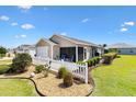 Well-maintained home featuring a white picket fence, an enclosed porch, and a beautifully landscaped yard at 1486 Olympia St, The Villages, FL 32163