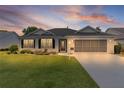 Beautiful single-story home with a well-kept lawn, screened garage, and inviting entrance at sunset at 17036 Se 79Th Clearview Ave, The Villages, FL 32162