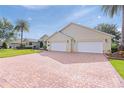 Expansive brick driveway leads to a home with a three-car garage and manicured landscaping at 1721 Sunset Ridge Dr, The Villages, FL 32162