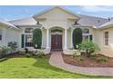 Charming home entrance features a brick path, manicured bushes, and decorative columns at 1721 Sunset Ridge Dr, The Villages, FL 32162