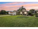 Charming single-story home with well-manicured lawn, a palm tree, and vibrant sunset sky at 2139 Kaylee Dr, The Villages, FL 32162