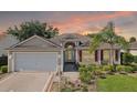Charming single-story home with tan siding, red shutters, well-manicured landscaping, and two-car garage at 2139 Kaylee Dr, The Villages, FL 32162