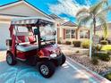 View of a golf cart parked in the driveway of a well-maintained home with manicured landscaping at 2139 Kaylee Dr, The Villages, FL 32162