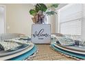 Well-appointed dining table featuring a 'Welcome Home' centerpiece, inviting wicker chairs, and natural light at 2293 Wayland St, The Villages, FL 32162