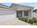 Inviting front entrance with a pristine white garage door, covered porch, and neatly trimmed shrubbery at 2293 Wayland St, The Villages, FL 32162