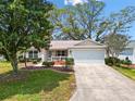 Charming single-story home with a two-car garage, lush landscaping, and an inviting entrance at 8097 Se 174Th Belhaven Loop, The Villages, FL 32162