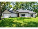 Charming single-story home featuring a two-car garage, well-manicured lawn, and neutral exterior paint at 10033 Canterbury Dr, Leesburg, FL 34788
