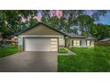 Charming single-story home featuring a two-car garage, well-manicured lawn, and neutral exterior paint at 10033 Canterbury Dr, Leesburg, FL 34788