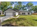 Charming single-Gathering home featuring a modern garage door and well-manicured lawn and landscaping at 10033 Canterbury Dr, Leesburg, FL 34788