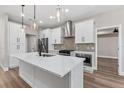 Modern kitchen with white cabinets, stainless steel appliances, range hood, and large island at 10033 Canterbury Dr, Leesburg, FL 34788