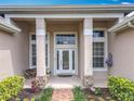 Detailed front porch with stone pillars, glass paned windows, and well-kept landscaping at 1473 Lakemist Ln, Clermont, FL 34711
