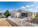Inviting light home featuring a screened porch, an attached garage, and a charming white picket fence at 1622 Navidad St, The Villages, FL 32162