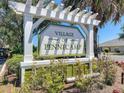 Welcome to Village of Pennecamp! Beautiful community sign with lush landscaping and vibrant greenery at 1842 Lake Ridge Dr, The Villages, FL 32162