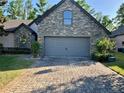 Stone-accented home exterior with paved driveway, complemented by lush greenery at 1893 Banning Beach Rd, Tavares, FL 32778