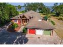 Aerial view of a lakefront property featuring expansive grounds, mature trees, and three-car garage at 2400 N Griffin Dr, Leesburg, FL 34748