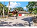 Charming home with a circular driveway, stone accents, three-car garage, and verdant landscaping at 2400 N Griffin Dr, Leesburg, FL 34748