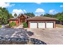 Charming exterior with red facade, 3-car garage, stone accents, and circular driveway at 2400 N Griffin Dr, Leesburg, FL 34748