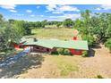 Stunning aerial view of the home with a green metal roof and sprawling green pastures at 274 W Kings Hwy, Center Hill, FL 33514