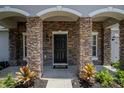 Stunning stone entryway with a black front door and manicured landscaping at 31920 Parkdale Dr, Leesburg, FL 34748