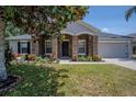 Charming home featuring stone accents, a well-manicured lawn, and a two-car garage at 31920 Parkdale Dr, Leesburg, FL 34748