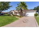 This attractive home features a decorative driveway, lush lawn, mature palm tree and welcoming curb appeal at 334 Shiloh Ct, The Villages, FL 32162