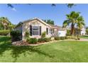 Attractive home boasts a lush green lawn, complemented by a mature palm tree and well-maintained landscaping at 334 Shiloh Ct, The Villages, FL 32162