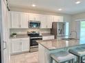 Modern kitchen featuring white cabinets, stainless steel appliances, granite countertops, and a center island with seating at 3638 Sw 127Th Lane Rd, Ocala, FL 34473