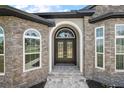 Close-up of the front entrance with stone accents, arched windows, and a double door with glass panels at 40050 Darlington Ave, Lady Lake, FL 32159