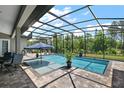 Screened-in pool area featuring an in-ground pool, patio furniture, and a view of the surrounding trees at 40050 Darlington Ave, Lady Lake, FL 32159