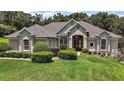 Landscaped front yard with manicured bushes frames a one story home with neutral stucco at 7249 Chesterhill Cir, Mount Dora, FL 32757