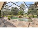 Spacious screened-in pool with stone patio, surrounded by mature trees and landscaping at 7685 Lake Angelina Dr, Mount Dora, FL 32757