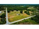 Aerial shot of a home and property with lush foliage and a distant pond under a clear blue sky at 7701 Groveland Farms Rd, Groveland, FL 34736